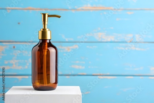 Amber glass dispenser bottle with gold pump on white pedestal