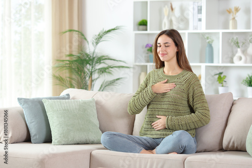 Woman in green doing healthy breath exercises at home