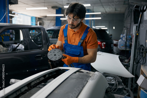 Photos Auto body technician sanding car panel in workshop - repair and refinishing proc