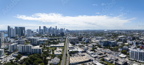 Aerial view of a sprawling cityscape where gleaming skyscrapers meet the vibrant urban grid, bisected by a long road under a vast sky, Edgewater, Miami, United States.