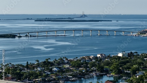 Aerial view of a bridge stretching across sparkling waters towards distant islands and the Sunshine Skyway Bridge, St. Pete Beach, Florida, United States.