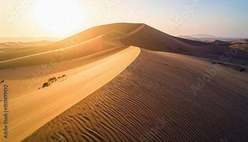 Fototapeta Naklejka Na Ścianę i Meble -  Vast desert landscape with rolling sand dunes illuminated by the warm glow of the setting sun, showcasing intricate sand ripples.