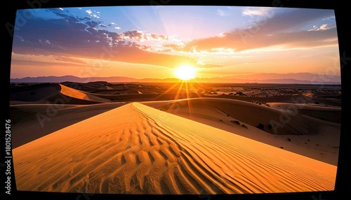 Fototapeta Naklejka Na Ścianę i Meble -  A vibrant sunset illuminates rolling sand dunes in a desert landscape, with sunbeams piercing through dramatic clouds.