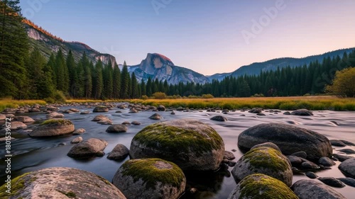 Majestic sunrise over yosemite national park with half dome in the distance. Long exposure of the merced river flowing over mossy rocks in the beautiful valley wilderness