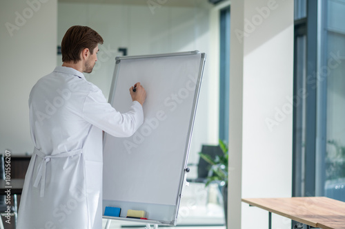 Physician standing by whiteboard ready for lecture indoors
