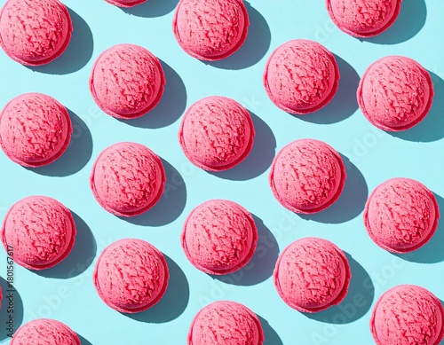 A vibrant, top-down flat lay of repeating scoops of bright pink strawberry ice cream arranged in a symmetrical pattern on a solid, bright teal background.