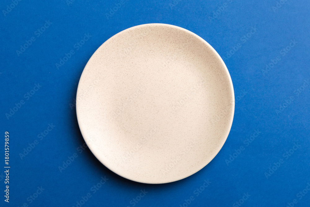 Obraz premium Top view of isolated of colored background empty round beige plate for food. Empty dish with space for your design