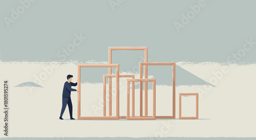 A businessman carefully arranges empty wooden frames to build a structure.