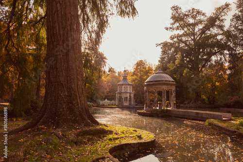 Autumn backlit view of a kiosk and small pavilion next to a lake