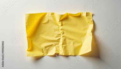 Crumpled yellow paper on light surface, textured abstract background