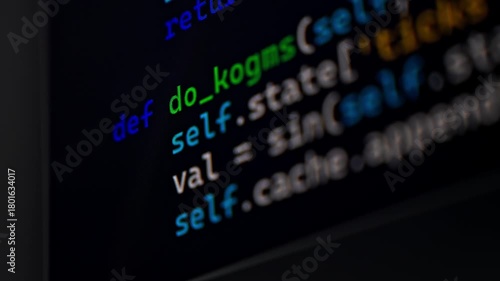 Closeup view of a computer monitor showing programming code on a dark background as someone types. Focus on screen details and syntax lines.