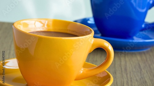 Two colorful coffee cups filled with a warm beverage