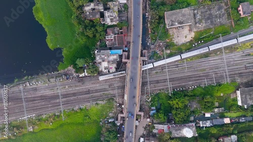 4k Top Down Aerial View of Train Passing Under Road Bridge Traffic near Green Lake in City.