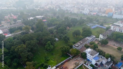4K Aerial Drone View of Hazy Urban Cityscape with Green Trees and Buildings in Heavy Smog.