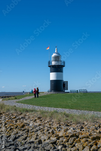 The small lighthouse in Wremen on the North Sea coast is open to visitors, with a footpath and a blue sky