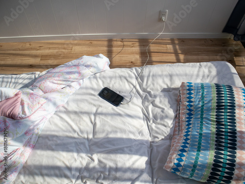 布団の上でスマホを充電している