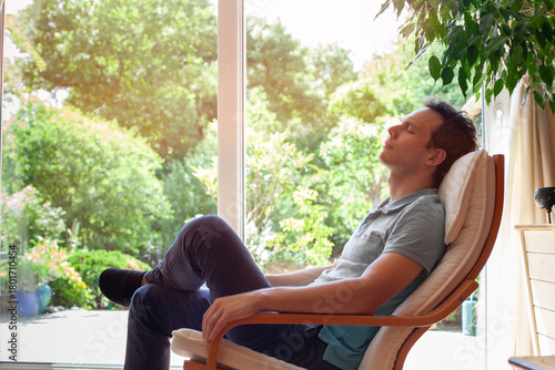 man relaxing at home after work, rest and relaxation for mental health and wellbeing, person with closed eyes sitting in armchair