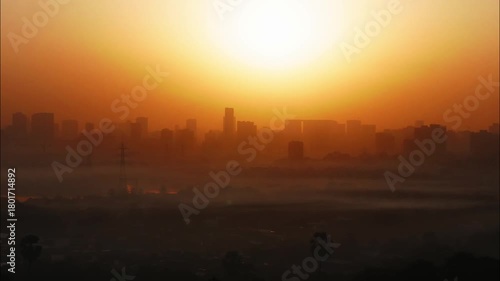 A beautiful time lapse of the sun rising behind an urban landscape of skyscrapers, turning the skies in different hues of orange, with clouds passing over a congested slum locality, Mumbai city, India