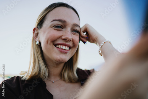 Close-up portrait of joyful woman smiling while using smartphone, representing happiness, positive online communication, digital lifestyle and cheerful emotional connection.