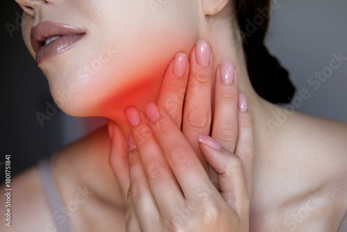 A woman is touching her neck with a pained expression, indicatin