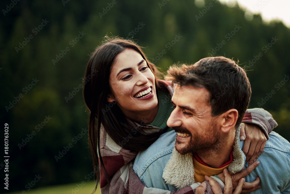 Fototapeta premium Happy couple enjoying piggyback ride in nature