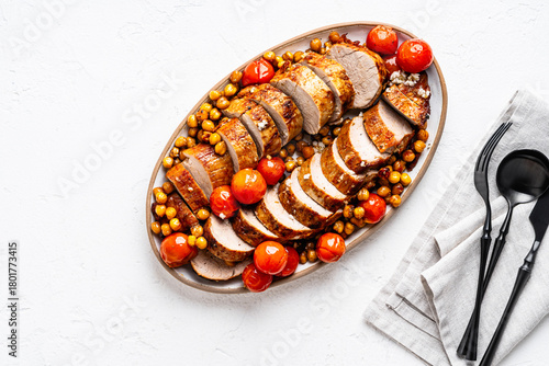 Roast pork tenderloin served with chickpeas and tomatoes in plate