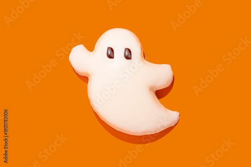 Ghost-shaped Halloween cookie on an orange background