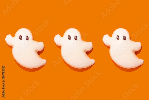 Ghost-shaped Halloween cookies on orange background