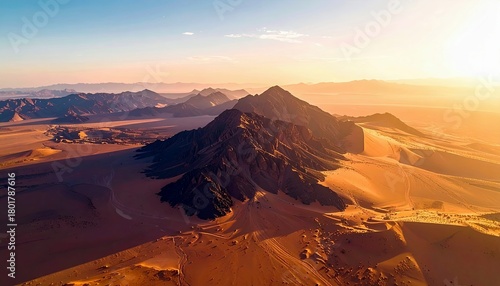Fototapeta Naklejka Na Ścianę i Meble -  An expansive desert landscape featuring dramatic mountains and rolling sand dunes, illuminated by the warm glow of the sun.
