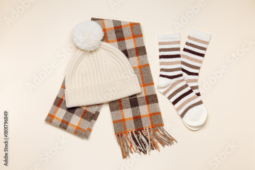 Winter fashion. Knitted hat with scarf and cute socks top view on beige background