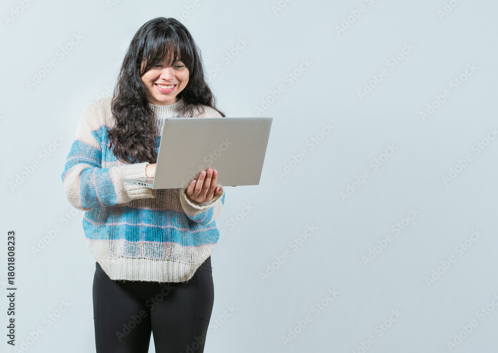 Naklejka premium Smiling asian girl holding and looking on laptop screen isolated. Portrait of beautiful asian woman using and looking laptop