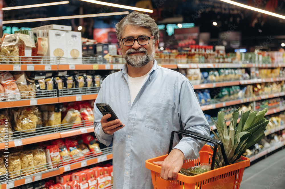 Obraz premium With big pineapple. A senior man is buying food in the grocery store