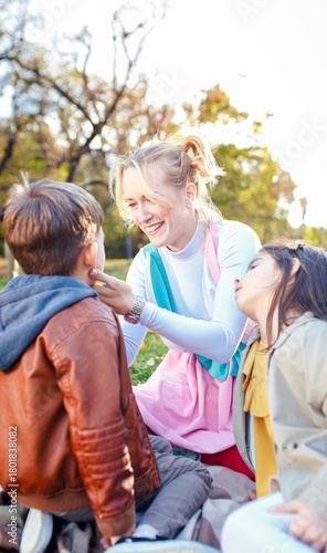 Female animator painting a child's face with a brush at an outdoor birthday party in a park.