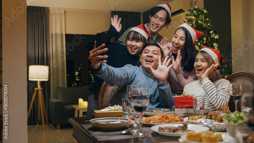 Group of Asia colleague gathering New year holidays party together. Happy friend group mobile phone video call online christmas thanksgiving dinner at home in evening, celebration and people concept.