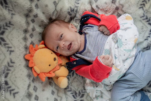 Newborn baby crying in bed with plush toy