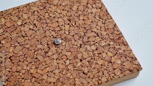 Close up of a cork board with a single silver tack.