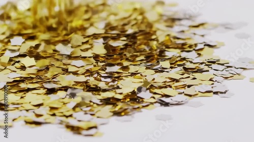 Close up of golden glitter falling onto a white surface.
