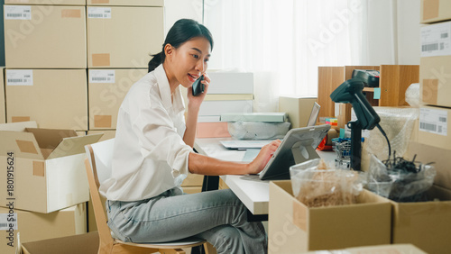 Fotografía Youth attractive Asia female entrepreneur small business start up call smartphone confirm order with customer confirm check stock inventory product ready for delivery shipment at online retail shop