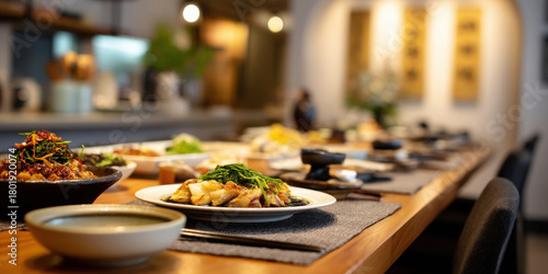 Asian chef table dining experience with plated seafood and greens, warm ambient restaurant interior, intimate communal meal