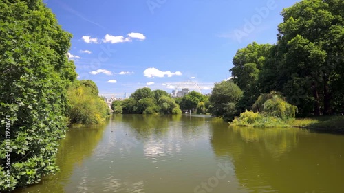 Peaceful view across the water in St James's Park surrounded by trees and summer foliage in London, UK