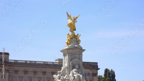 Victoria Memorial in front of Buckingham Palace with gold statue gleaming under blue sky in London, UK