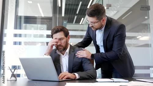 Businessman supports stressed colleague at workplace in business office. Male coworker supporting upset worried friend in depression and problems at work. Manager comforting employee with mental pain