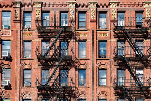A close up of a typical Harlem residential building with red brick and decorative details over the windows.