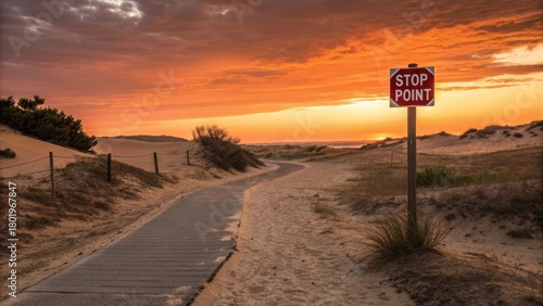 Desert path with a stop sign at sunset in the sandy dunes