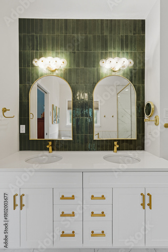 The bathroom is a modern and luxurious space with a green tile wall