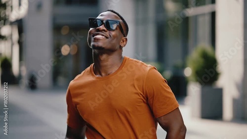 Modern Portrait of Fashionable African American Man in Orange Shirt Energetically Posing with Sunglasses
