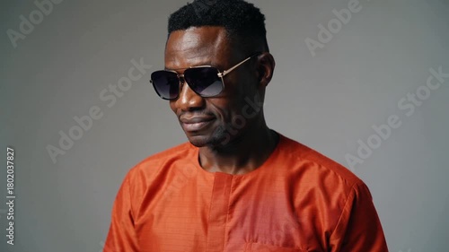 Expressive Studio Portrait of Fashionably Dressed African American Man in Orange Shirt with Sunglasses