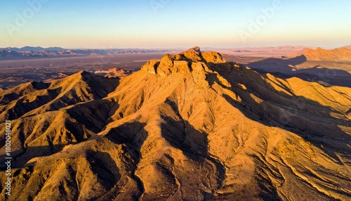 An aerial view of a vast mountain range illuminated by the warm, golden light of the setting sun.