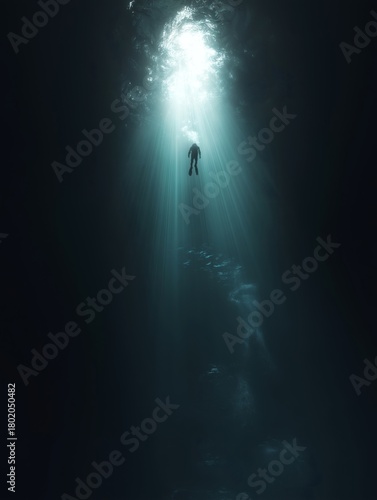 Diver ascending into light from the darkness of the ocean depths.