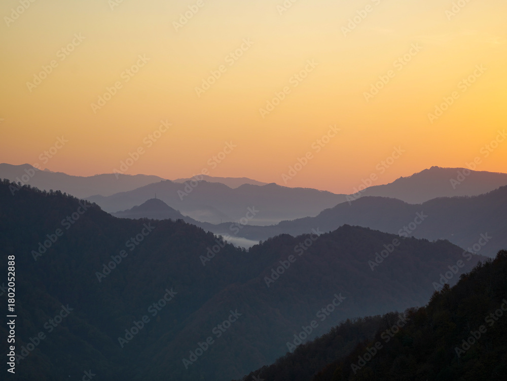Fototapeta premium A mountain range at sunset with a golden sky. 